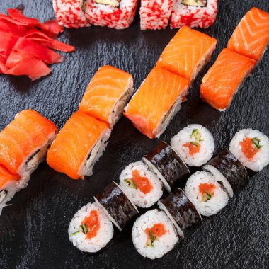 Japon mutfağı. Siyah arka planda taze malzemeli suşi. Farklı roller.