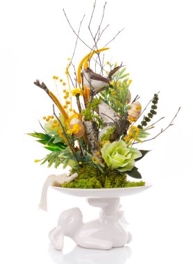 Dekoratif Paskalya kompozisyonu. Bir vazo standı, bir tavşan çiçeklerden oluşan bir kompozisyon tutar. Beyazda izole edilmiş.