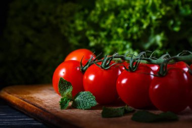 Güzel kırmızı olgun domatesler. Karanlık arka plan, ışık domateslerin üzerine düşüyor. Afiş reklamı için fotoğraf. Promosyon çekimi. Metin için yer.