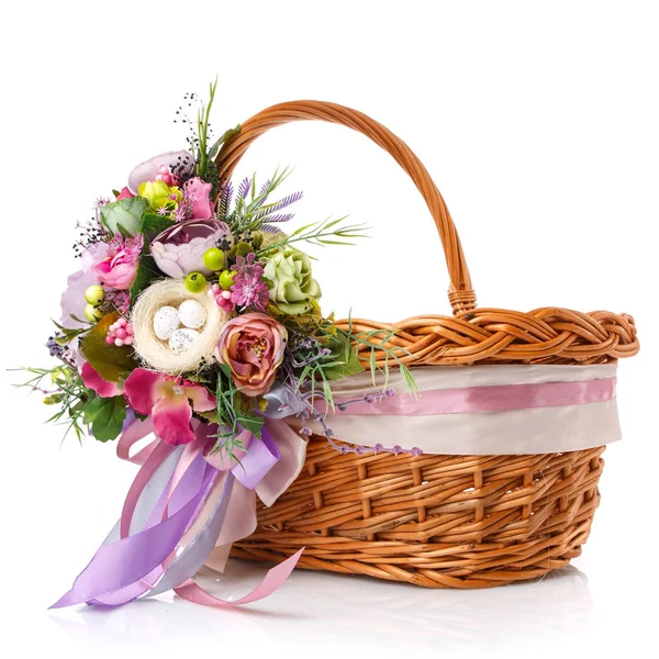 Easter basket. Brown wicker basket with colorful floral decor and colored ribbons on a white background. Beautiful basket design for Easter celebration.