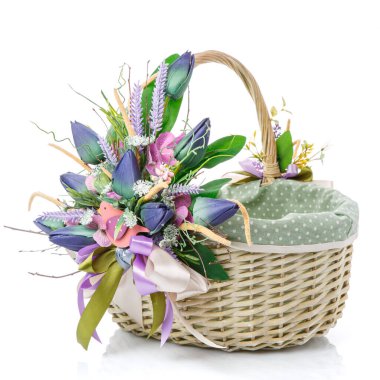 Paskalya sepeti. Beyaz arka planda kumaş var. Büyük mavi laleler, yeşillik ve dekoratif ahşap kuşlarla süslenmiş. Yan görüş. İzole edilmiş