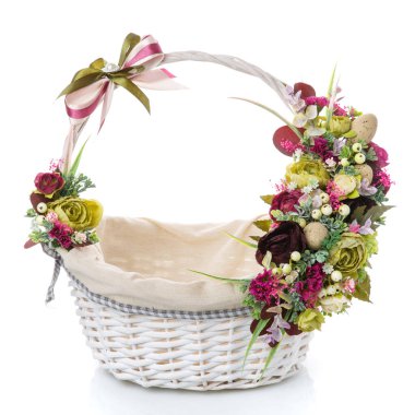 İçinde kumaş olan beyaz hasır sepet. Çeşitli küçük çiçekler ve yumurtalarla süslenmiş. Bir beyazda izole edilmiş.