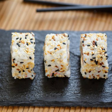 Japon suşi ruloları üzerine siyah ve beyaz susam tohumları serpiştirilmiş..