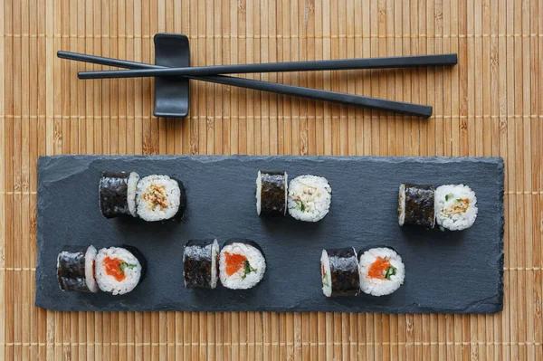 Sushi Egy Fekete Kőtáblán Friss Sushi Lazaccal Avokádóval Angolnával Felülnézet — Stock Fotó