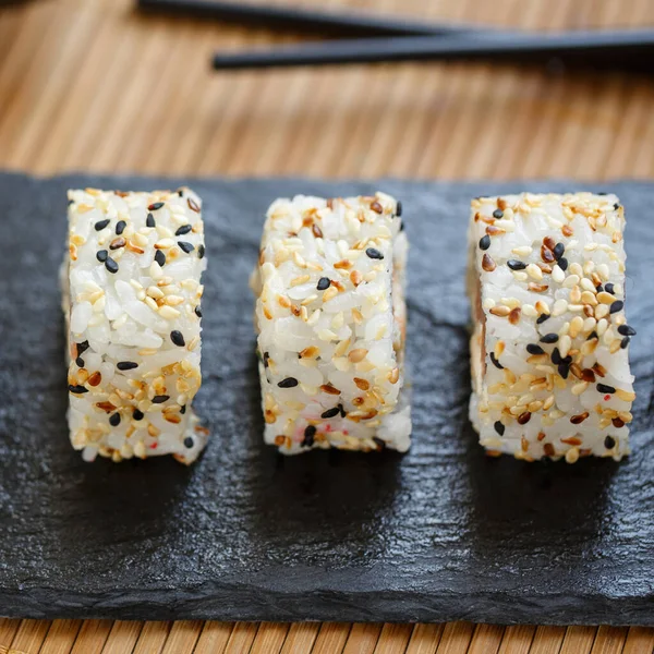 Japon suşi ruloları üzerine siyah ve beyaz susam tohumları serpiştirilmiş..