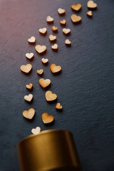 Gold-Geschenkbox und Dekor-Komposition mit schönen dekorativen Herzen aus Holz auf schwarzem Brett. Valentinstag oder Geburtstag Hintergrund. — Stockfoto