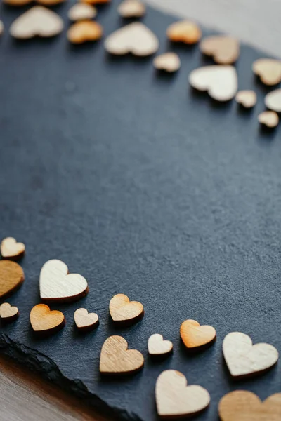 Heart shape made of natural wood. Beautiful heart shaped wooden little hearts on black background. Place for text.