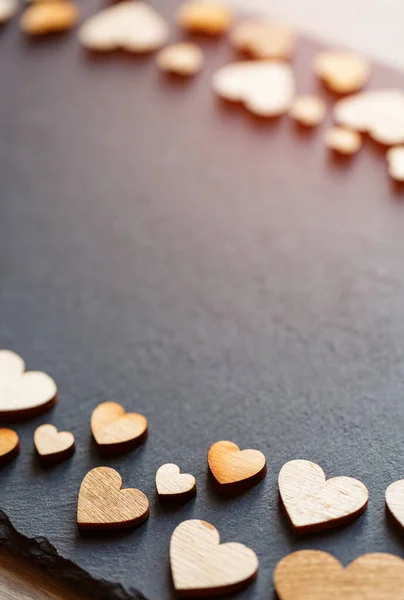 Fondo del día de San Valentín. Pequeños corazones de madera en tablero negro . —  Fotos de Stock