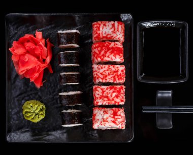 Koyu taştan bir arka planda Japon suşisi. Zencefil, wasabi ve soya soslu suşi seti. Çubuklarla servis et. Üst manzara, siyah arkaplan. Asya ya da Japon gıda çerçevesi.