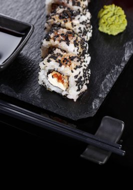 Geleneksel Japon Mutfağı. Sushi böreği, çubuk ve soya sosuyla servis edilir. Siyah tahtada, wasabi ve zencefil ile süslenir. Suşi menüsünün maketi.