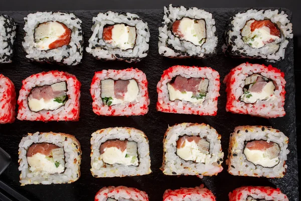 寿司卷日本食物在餐馆 不同类型的寿司卷与鲑鱼 鱼子酱和芝麻在一个黑色的背景 日本餐馆菜单 顶视图 — 图库照片
