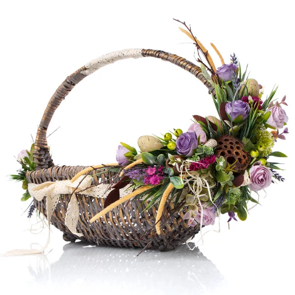 Orijinal saplı kahverengi hasır sepet. Çiçekli, yumurtalı ve kurdeleli. Paskalya kutlaması için yapıldı. Beyaz bir arkaplanda izole edilmiş