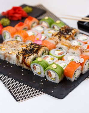 Suşi seti. Zencefil ve wasabi soslu farklı türde Maki ve Nigiri suşisi. Restoranda parlak ve renkli bir tören. Koyu taş suşi tahtalarında servis edilmiş. Kocaman bir suşi seti..