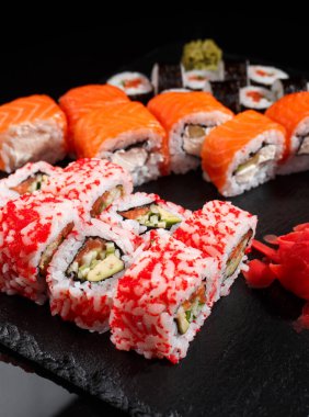 Farklı türde Japon suşisi, geleneksel ekmek ve siyah tahtada wasabi ve zencefilli maki. Yemek ve restoranlar..