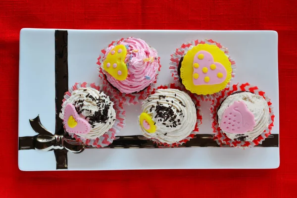 Love Muffins, bunte Cupcakes mit Marzipanherzen in weißer Keramik-Untertasse serviert, Blick von oben — Stockfoto