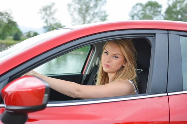 Frowning giovane ragazza bionda in auto rossa — Foto Stock
