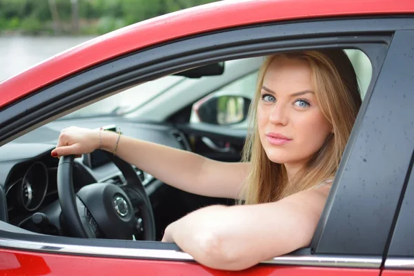 Jeune blonde aux yeux bleus regarde par la fenêtre de la voiture — Photo