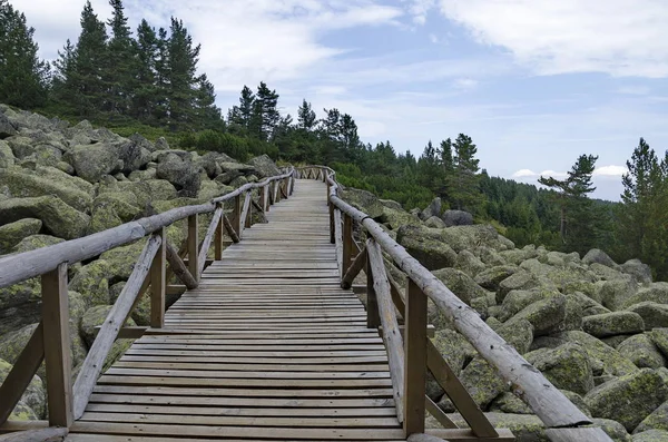 Unique stone river with big granite stones or moraine and wooden bridge — Stock Photo, Image