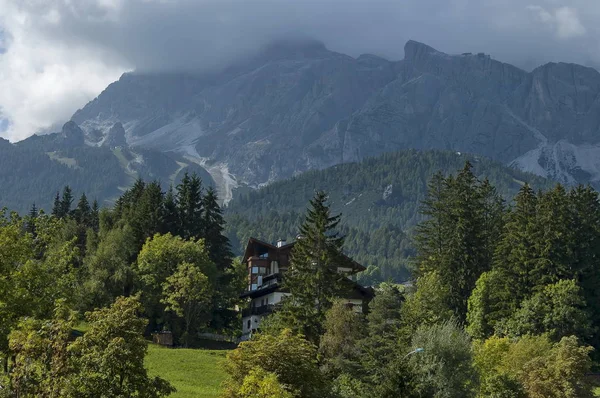 Autumnal corso Italia, the residential district in the town Cortina d 'Ampezzo with meadow and mountain, Dolomite, Alps, Veneto — стоковое фото