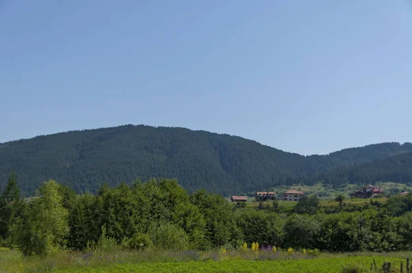 Scene with mountain top, forest, glade and residential district of bulgarian village Beli Iskar, Rila mountain — Stock Photo, Image