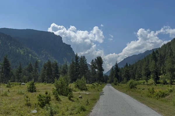 Majestátní vrchol hory zarostlé jehličnatého lesa, údolí, glade a silnice, hory Rila — Stock fotografie