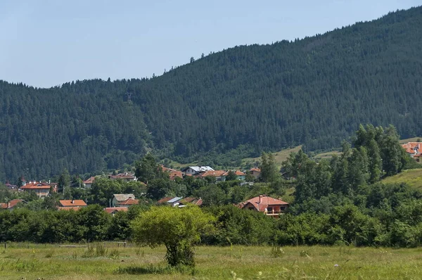 Scena con cima di montagna, foresta, radura e quartiere residenziale del villaggio bulgaro Beli Iskar, montagna di Rila — Foto Stock