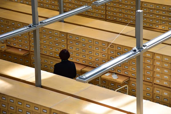 Βιβλιοθηκάριος μεταξύ ξύλινα ντουλάπια με ένα ντουλάπι αρχείο στο Ζυγό — Φωτογραφία Αρχείου