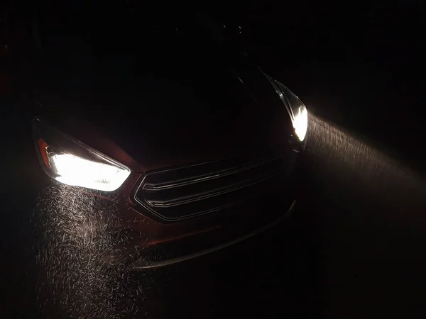 Headlights of the car shine at a heavy snowfall