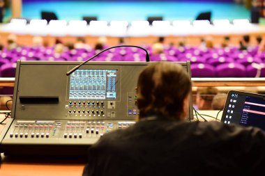 Ses mühendisi bir konser salonundaki müzik konsolunda oturuyor.