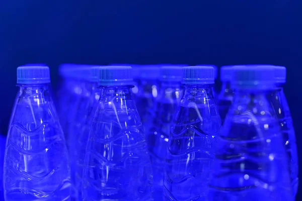 Garrafas de água potável limpa em um fundo azul — Fotografia de Stock