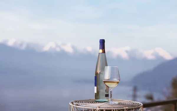 A glass of wine and a bottle of wine with a mountains view