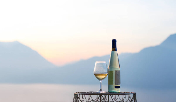 A glass of wine and a bottle of wine with a mountains view
