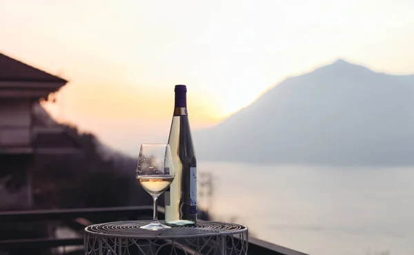 A glass of wine and a bottle of wine with a mountains view