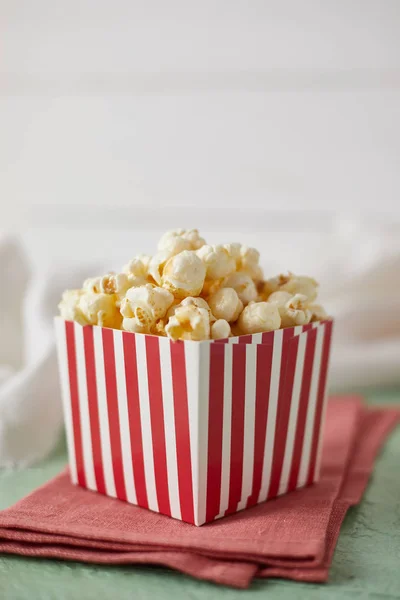 Full of tasty caramel popcorn in classic striped box — Stock Photo, Image