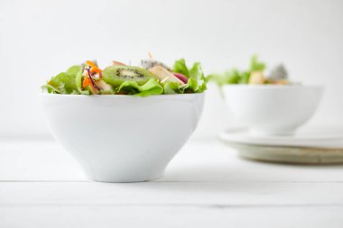 Lezzetli meyve salatası ve beyaz masada farklı meyveler.