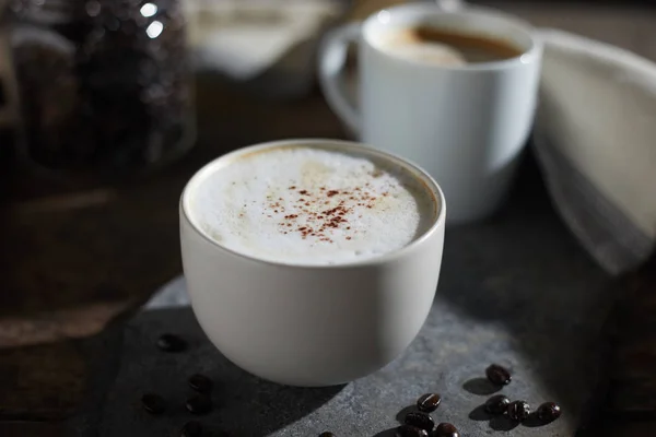 Hot coffee cup and coffee beans on wooden table