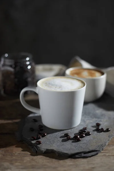 Taza de café caliente y granos de café en mesa de madera — Foto de Stock