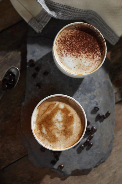 Taza de café caliente y granos de café en mesa de madera — Foto de Stock