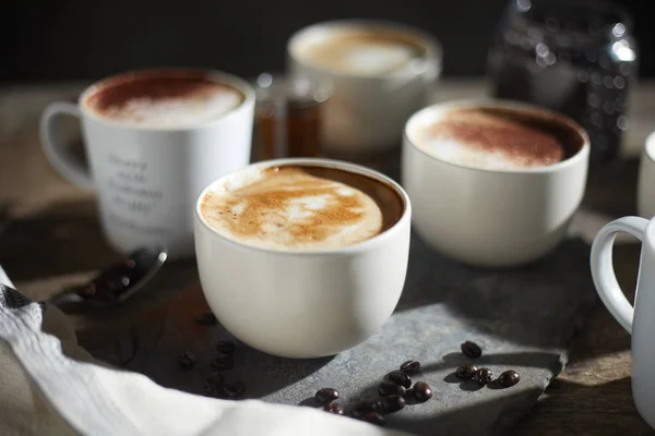 Taza de café caliente y granos de café en mesa de madera — Foto de Stock