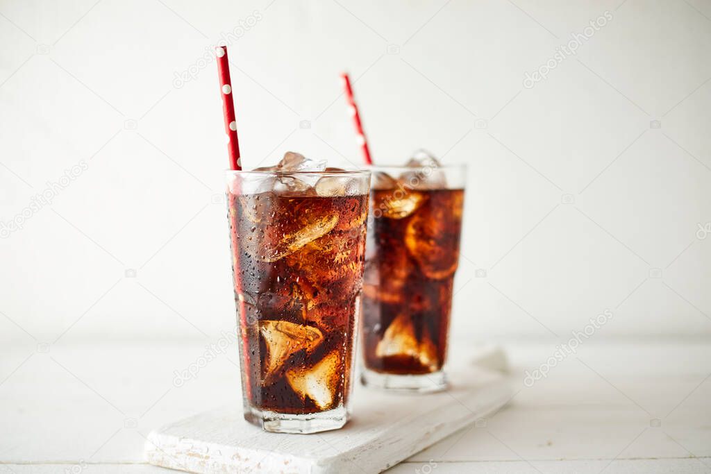 Close up glass of refreshing cola with ice on table