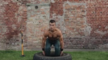 Lastik tutan ve çömelme hareketleri yapan yakışıklı bir genç.