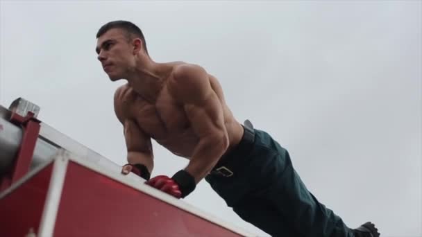 Bottom view van gespierde jonge man doen push-ups op de top van rode auto — Stockvideo