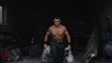 Yakışıklı üstsüz bir itfaiyeci iki elinde de yangın hortumu tutarak saldırıyor. Arka planda itfaiye ekipmanları