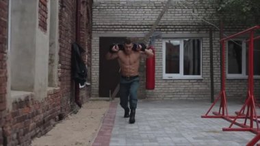 Omuzlarında ağırlık taşıyan güçlü, yakışıklı sporcu hamleler yapıyor. Sokak çalışması