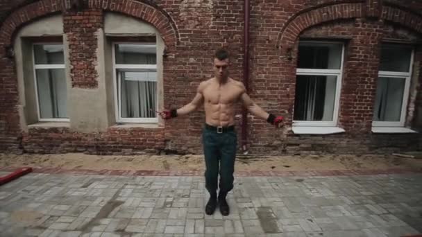 Handsome sportsman with nude torso jumping over skipping rope outdoors. Close view — Stock Video