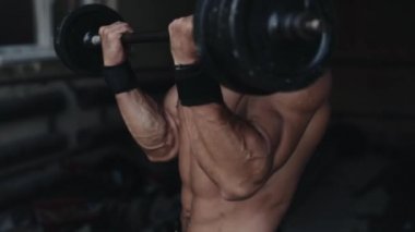 Spor salonunda halter kaldıran güçlü bir sporcunun yan görünüşü