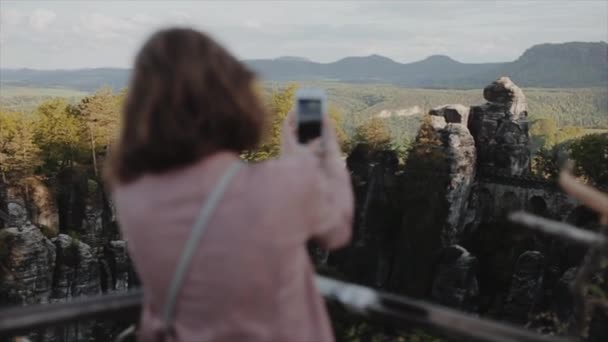 Dresde, Alemania - 12 de agosto de 2019: cámara lenta. Vista trasera cercana de la joven tomando fotos en su teléfono de hermosas montañas y rocas. Dándose la vuelta y haciendo selfie. Cambio de enfoque de la — Vídeos de Stock