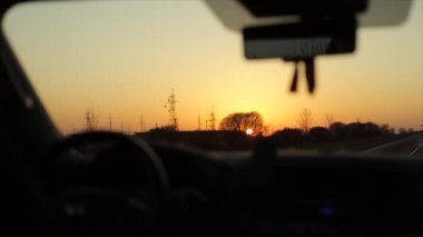 Gün doğumunda asfalt yolda araba sürüyorum. Arabanın içinden bak.