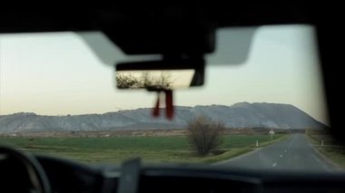 Gün doğumunda asfalt yolda araba sürüyorum. Arabanın içinden bak.