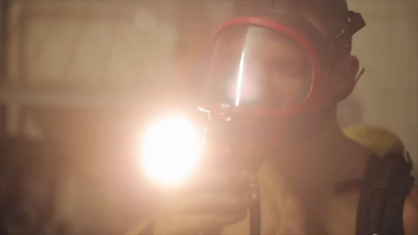 Nahaufnahme eines Feuerwehrmannes, der sich eine Sauerstoffmaske über das Gesicht zieht und davonläuft. blendendes Licht im Hintergrund — Stockvideo